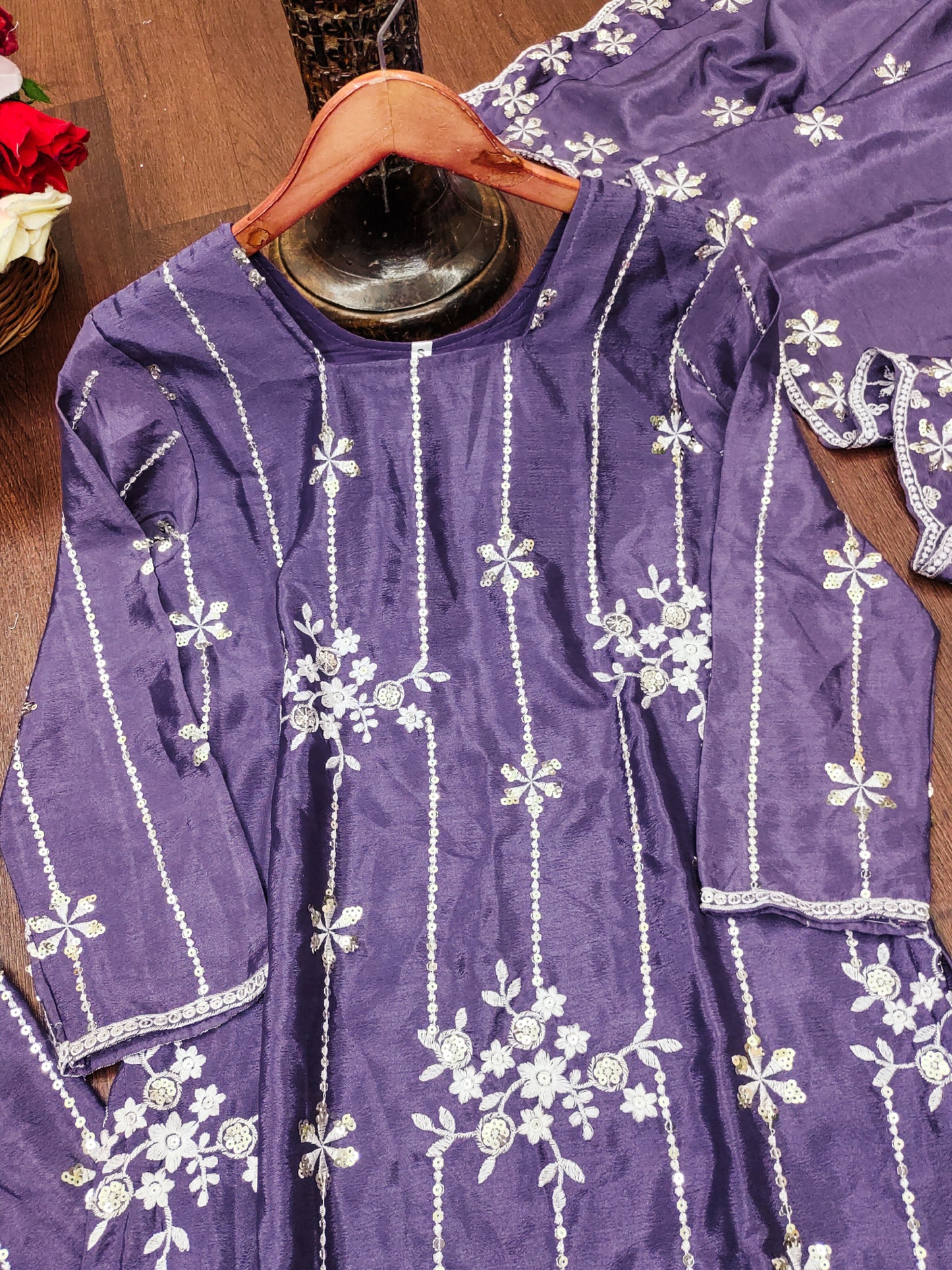 Purple embroidered outfit on a hanger with a wooden background