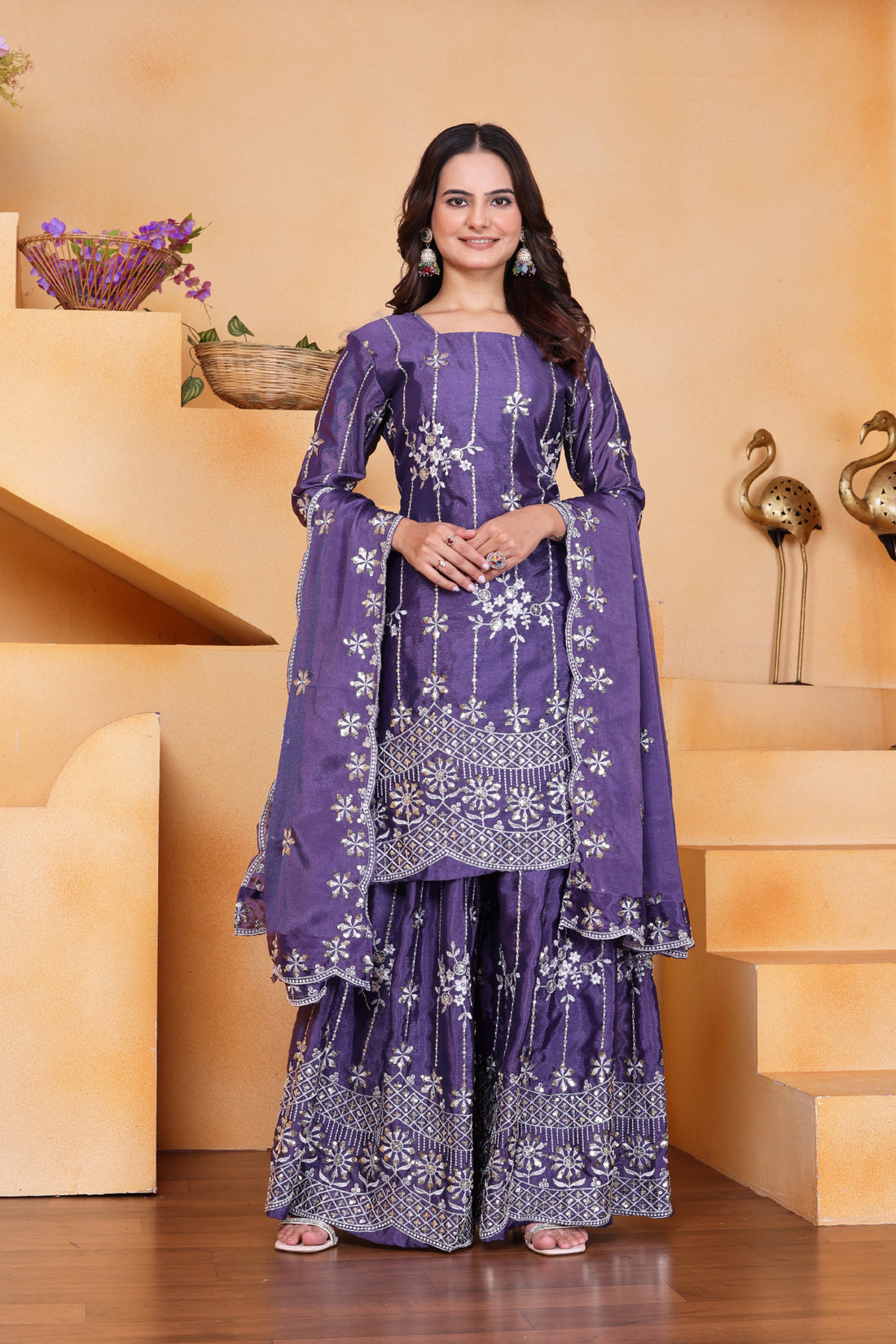 Woman wearing a purple traditional outfit with white patterns in a decorative setting.
